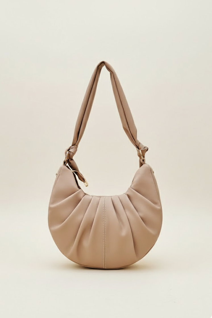 Beige half-moon women’s shoulder bag with pleated front and knotted padded strap.