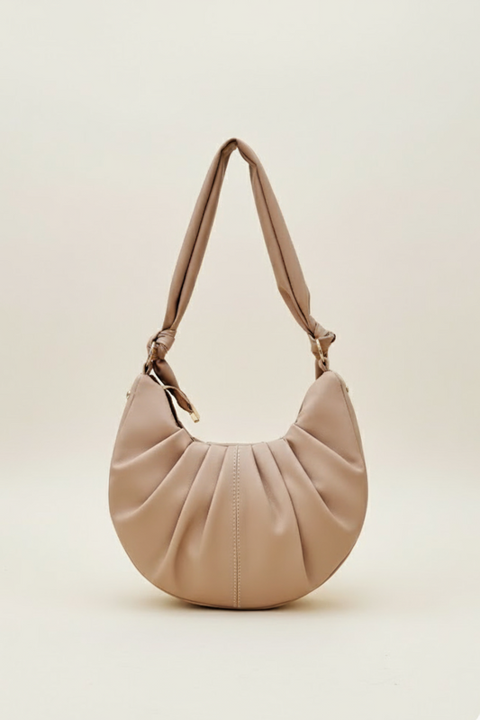Beige half-moon women’s shoulder bag with pleated front and knotted padded strap.